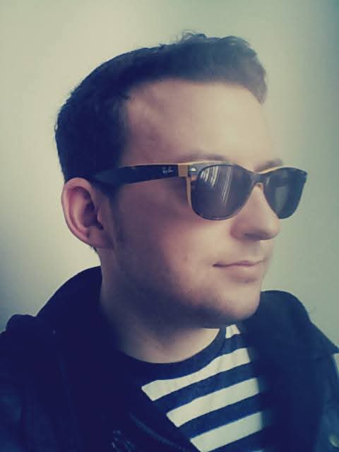 Justin Sovine in sunglasses, a dark jacket and a striped shirt, looking off to the side