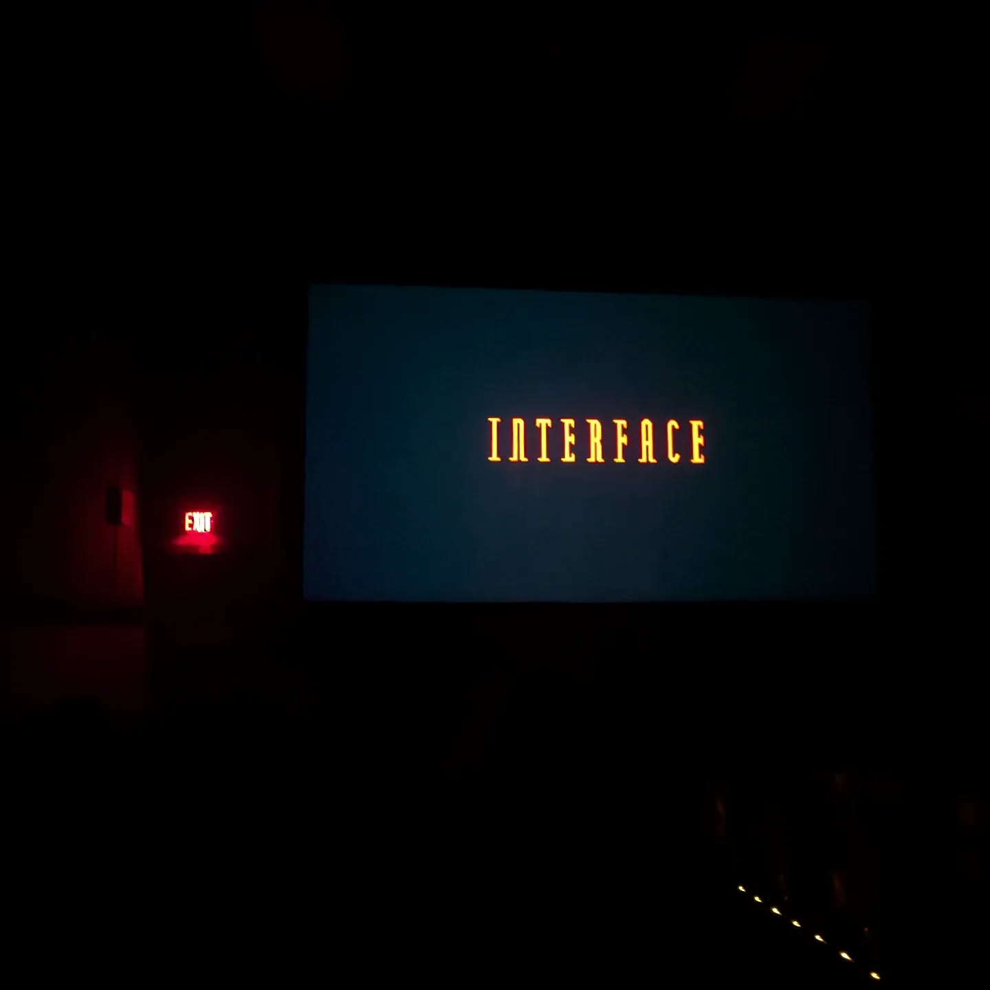 The Interface title on the screen at the Esquire, in the dark, beside a red exit sign