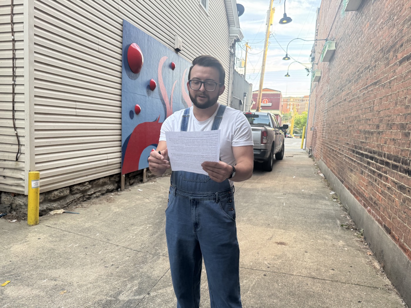 Justin Sovine in overalls, reading over the introduction outside before doors